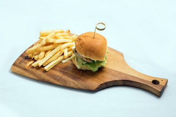 A low contrast Hero Shot of a grilled chicken slider burger, fries on a wooden platter board, on a...