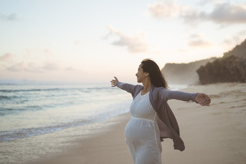 happy pregnant women standing on the beach when they see the ocean