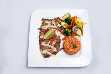 A Hero shot of a grilled fish fillet gratini with vegetables & lentils on the side, on a white plate, minimal background with a 60 degree front facing perspective.