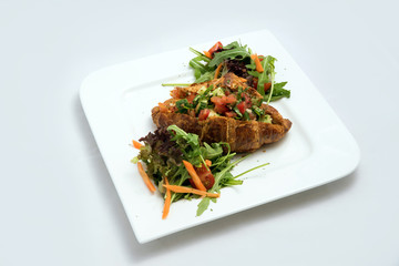 A low contrast Hero shot of a breakfast platter with vegetable-filled croissant with vegetables- carrot, tomato, lettuce on a minimal white background with a 30 degree angle from diagonal perspective.