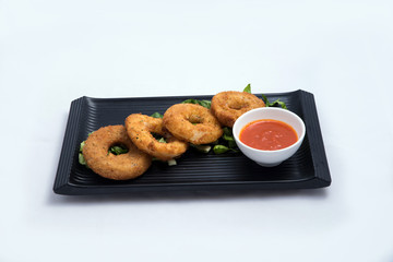 A low contrast Hero shot of an appetizer platter of onion rings with lettuce and tomato chutney on a minimal white background with a 45 degree angle front perspective