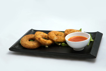 A low contrast Hero shot of an appetizer platter of onion rings with lettuce and tomato chutney on a minimal white background with a 45 degree angle front perspective