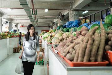 pregnant asian young woman standing carrying plastic bag when shopping at the market