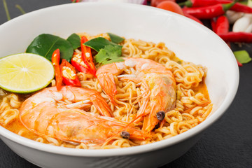 Instant noodles, Tom Yum Kung flavor Spicy, spicy flavor with Thailand spices placed on the table, black background.
