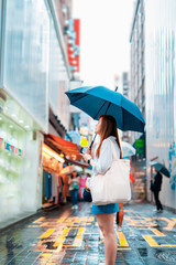 spring and raining season activity concept from beauty asian woman travel and shopping with hold her umbella with city and street food market background