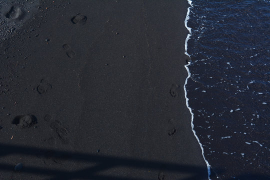Backdrop Stromboli beach, black volcanic sand with footsteps