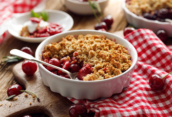 Cherry crumble in a baking dish on a wooden table, close-up