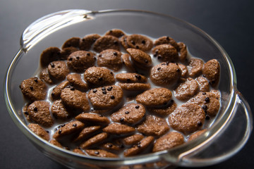 Chocolate muesli in milk on glass plate with backlight
