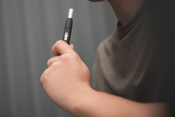  Tobacco product technology. Newest electronic cigarette. Heating tobacco system. Man holding e-cigarette in his hand before smoking. Close-up.