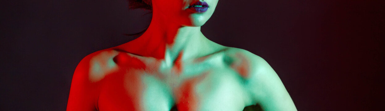 Slender girl with bare shoulders in the studio with color absorbers