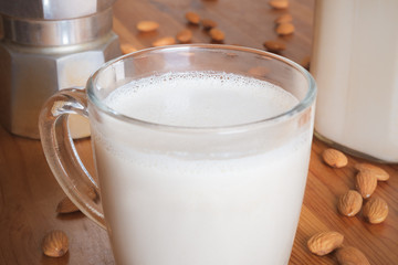 Glass of almond milk  on wood table, close-up view. Vegan almond drink in a jar - plant based substitutes of milk products