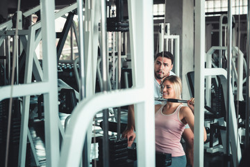 Fototapeta na wymiar Beautiful Woman is Exercised Training With Bodybuilder Machine in Fitness Club., Attractive of Sporty Girl Doing Working Out With Her Trainer in Gym, Healthy and Sport Exercising Lifestyle Concept.