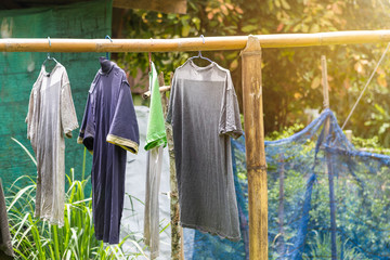 Wet old t-shirt hanging on bamboo rail, outdoor day light