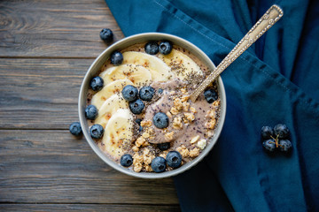 Healthy breakfast berry smoothie bowl topped with banana, granola, Blueberries and chia seeds with copy space