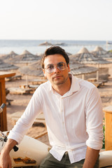 beautiful sunrise on the sea. sand beach. The guy in the white shirt and glasses. Tourist vacation at sea.