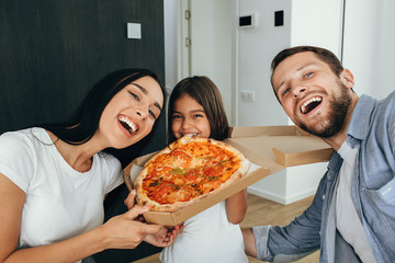 Family enjoying pizza lunch. Little girl having fun with her family