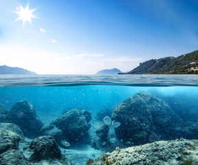 Fototapeta premium Blue sunny sky, an island in the ocean and underwater sandy rocky sea view.