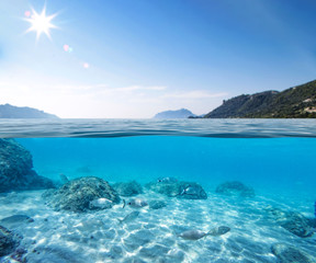 Fototapeta na wymiar Blue sunny sky, an island in the ocean and underwater sandy rocky sea view.