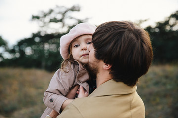 Young father and little toddler daughter girl kissing each other in the autumn forest.