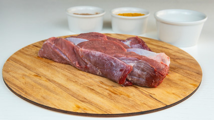 Fresh slice of beef close-up. Preparation for cooking red meat with spice and tomato.