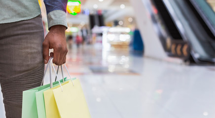 Unrecognizable african man holding shopping bags in city mall