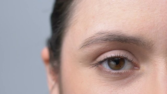 Woman rolling her red overworked eyes irritated with job, face close-up