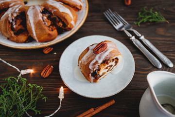 Piece of Swedish tea ring Christmas cake with cinnamon, pecans and raisins on a warm knitted sweater. The concept of cozy winter Holidays and homemade bakery.