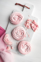 Top view of pink meringue on a white marble tray. Flat lay composition.