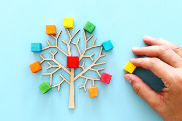 Business image of wooden tree with colorful cubes over blue table, human resources and management...