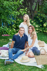 family father, mother and daughter in the garden in the summer on a picnic rest
