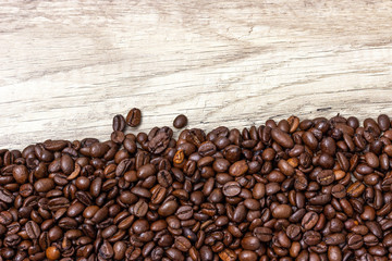 Roasted coffee beans, on a wooden surface.
