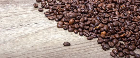 Roasted coffee beans, on a wooden surface.