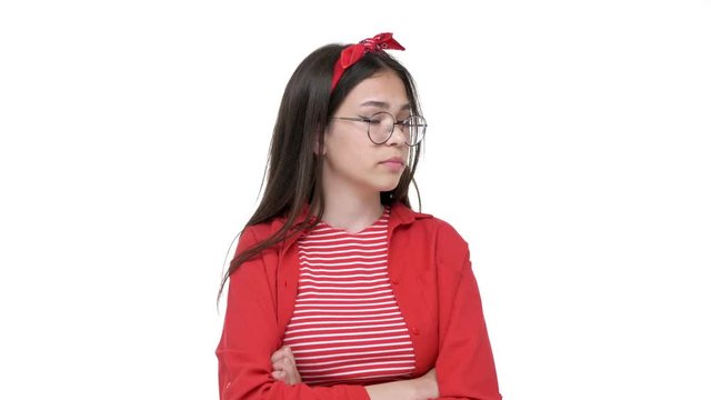 Upset young brunette girl in red shirt with resentful look and crossed hands while looking at the camera over white background isolated