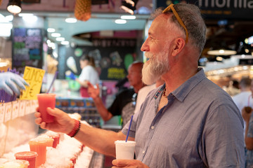 Old man with white beard buying a soda at the market