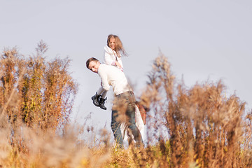 Happy dad and daughter posing among autumn yellow dry plants