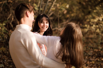 Fototapeta premium Dad, daughter and mother spend time together in the autumn forest. Mom looks at daughter with love