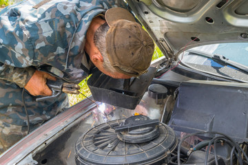 Auto mechanic repairs an old car