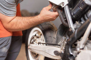 mechanic close up repairing motorbike in repair garage .