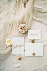 Flat lay wedding set of fine art calligraphy, david austin rose, pure silk ribbons, envelopes and invitations on beige silk
