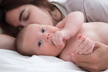 Baby and mom. A brunette woman lies with a blond child. Top view