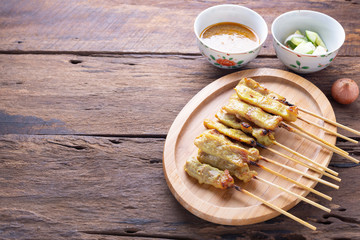 Pork satay - Grilled pork served with peanut sauce or sweet and sour sauce - Asian food style on wood table