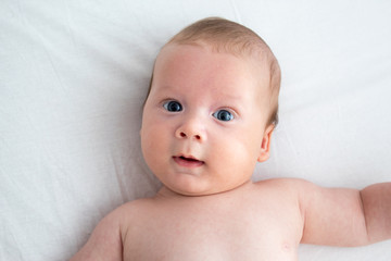 The baby smiles. Newborn lying on a white background .Top view
