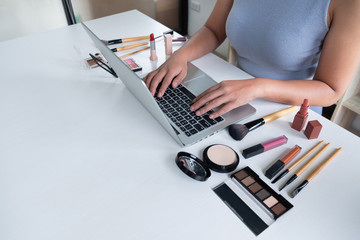 woman blogger present cosmetic product sitting in front tablet and broadcast to social network by...