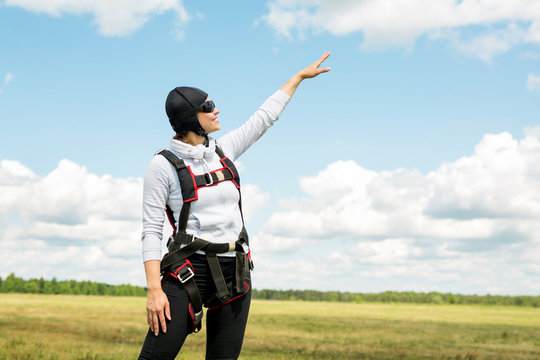 beautiful young woman in parachuting gear against the sky with clouds