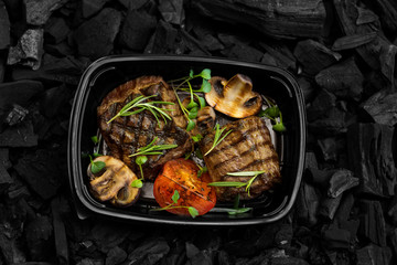 Fresh grilled meat steak with vegetables in black box on charcoal
