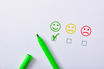 Positive satisfaction with green marker represented with emoticons on paper