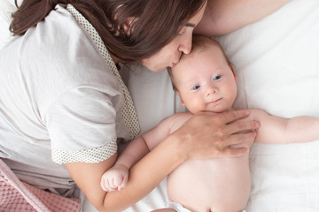 The mother kisses the baby . The brunette lies with a blind child. Top view