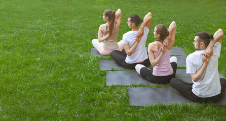 Friends making yoga exercises with hands hooked behind the back