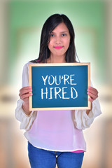 Young Women holding chalkboard with text You're hired