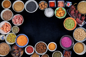 Bowls with species on black background. Hibiscus, yellow lentils, green lentils, pink arooz, star anise, chickpeas, sesame, oat seeds